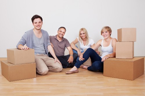 Local movers carrying furniture through a flat building corridor